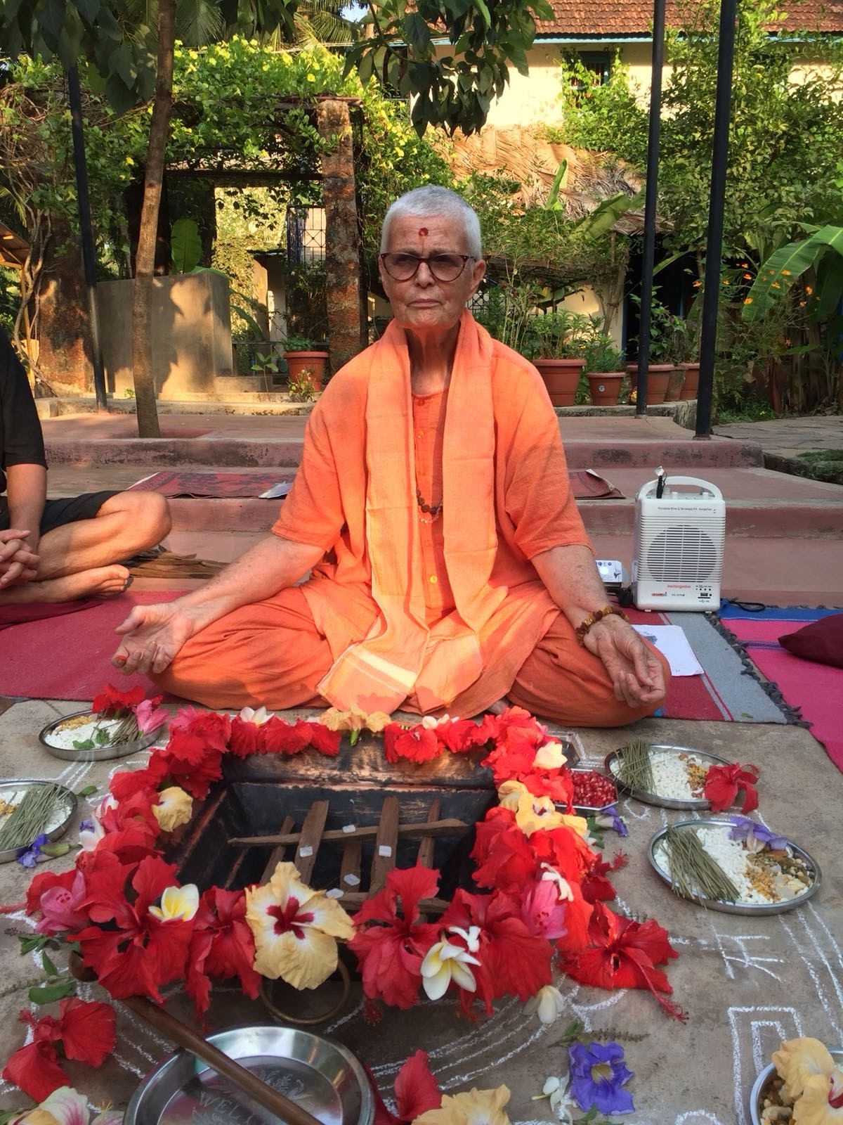 Swamiji at the havan fire, ringed with flowers