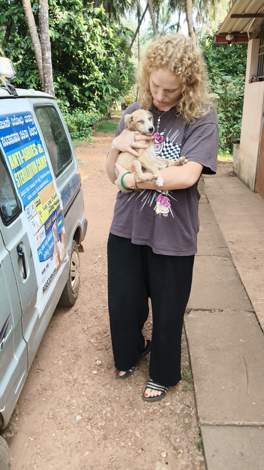 A volunteer and a puppy beside the sterilization-camp van